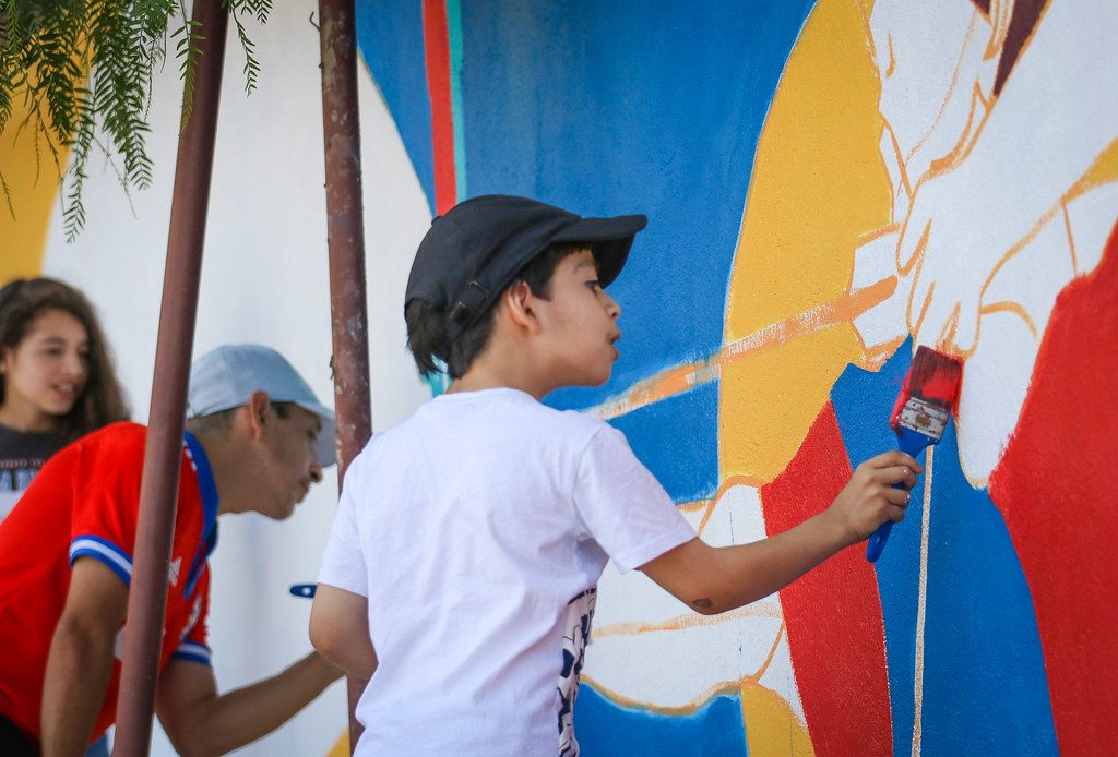 Estudiantes pintando un mural colaborativo